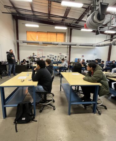 Visiting Kodiak representative stands at front of classroom to speak to students about his company.