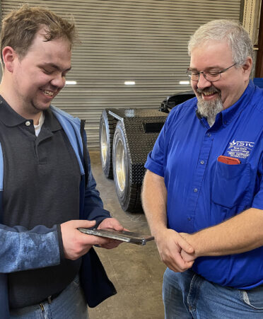 two men looking at a metal plate