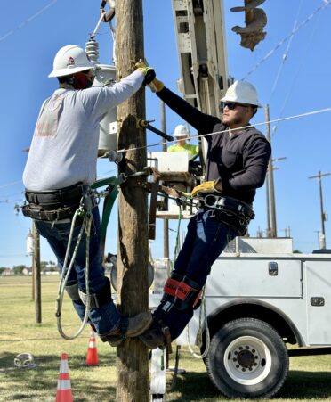 TSTC Electrical Lineworker and Management Technology students Oswaldo Arriasola (right) and Julio Cepeda (left) help each other install a transformer on a practice utility pole during a recent lab session.