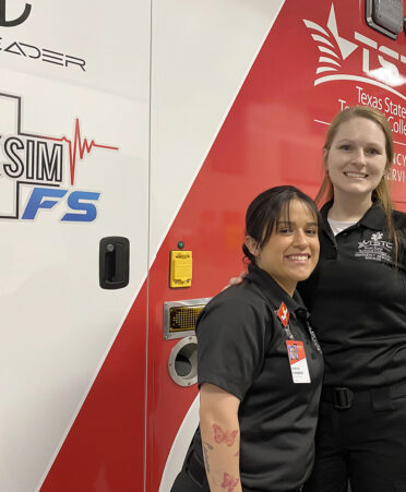 Two women standing in front of an ambulance