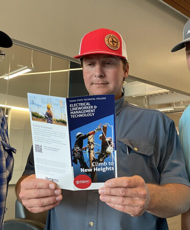 three men wearing hats looking at a brochure