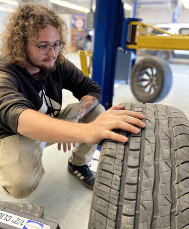 man in black shirt looking at tire