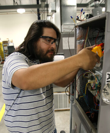 Eliseo Alcala III, a TSTC HVAC Technology student, checks the amperage to a residential air conditioning unit during a recent lab session.