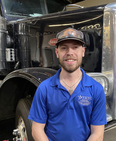 man in blue shirt standing in front of truck