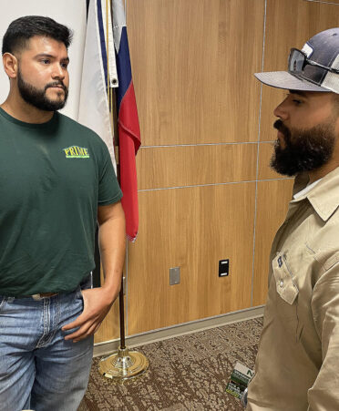 man in green shirt and man in hat talking