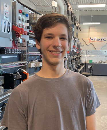 man in gray shirt standing in front of electrical board