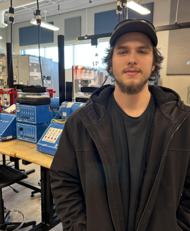 man in brown jacket standing in front of lab equipmen t