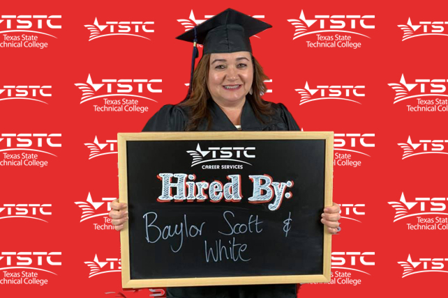 TSTC graduate posing in cap & gown holding a chalkboard showcasing their new employer.