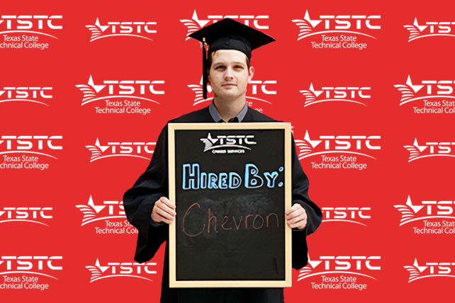 TSTC graduate posing in cap & gown holding a chalkboard showcasing their new employer.
