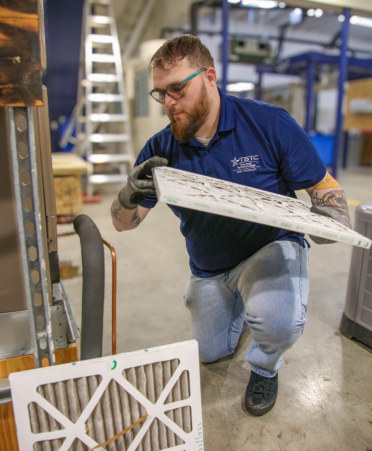 Regan Youngers, a TSTC HVAC Technology student, replaces an air filter on a residential air conditioning unit during a recent lab session.