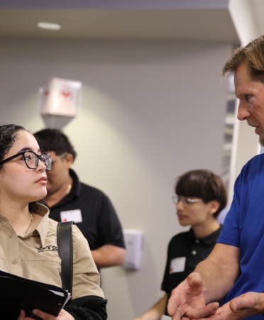 A student wearing a tan shirt meets with an employer wearing a blue shirt.