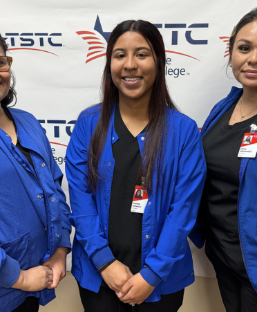 three nursing students in blue scrubs