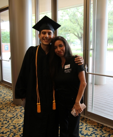 Noah wearing cap and gown hugs a TSTC employee while both pose for the camera.