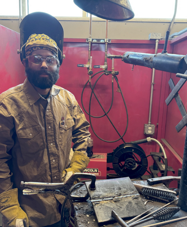 man in welding gear inside a booth