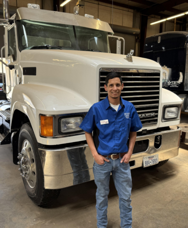 man in blue shirt standing in front of semi truck