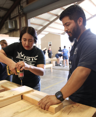 Carlos Rodriguez (right), a Building Construction Technology instructor at TSTC’s Harlingen campus, guides volunteer Cassandra Garcia, an LVN to RN Transition Nursing student at TSTC, in properly using a drill to secure nails in wood during the recent Build-a-Bed Build Day event.