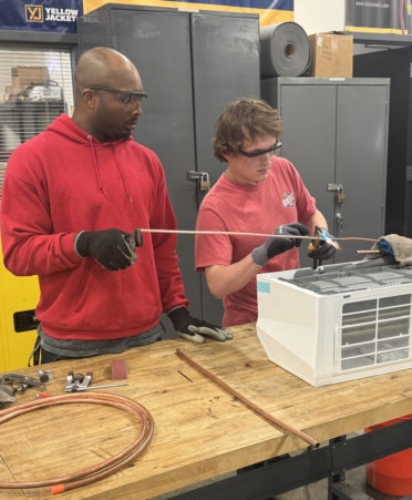 Elijahwah McCowan (left) and Edward Wilds, two HVAC Technology students at TSTC’s North Texas campus, repair a mini-split system for the campus’s IT room. (Photo courtesy of TSTC.)