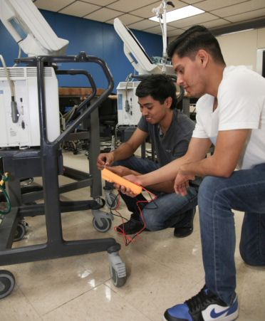 Israel Alanis, left, a Biomedical Equipment Technology student at Texas State Technical College’s Harlingen campus, checks for blown fuses on a ventilator, while classmate Ryan Montelongo assists by holding a multimeter during a recent lab session.