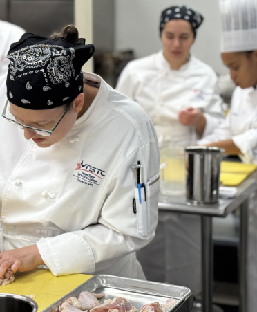 chefs cutting chicken in a kitchen