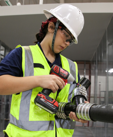 Sylvia Quintanilla, a Plumbing and Pipefitting student at Texas State Technical College’s Harlingen campus, uses a drill to secure hose clamps on a cast iron pipe during a lab session.