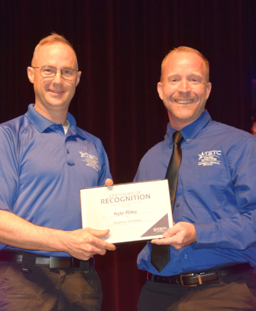 two men in blue shirts at center stage