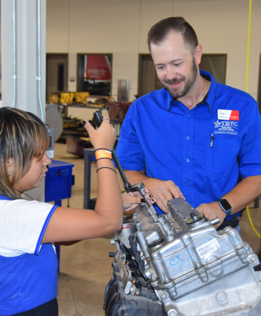 discovery day-7 man in blue shirt in front of engine