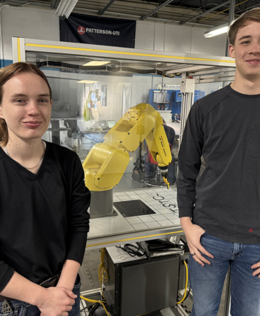 Skills-ETT Two people standing in front of robot