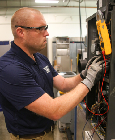 Austin Marshall, an HVAC student at Texas State Technical College’s Fort Bend County campus, checks the voltage level of a gas furnace control board during a lab session.