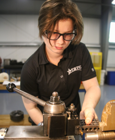 Anna Mohar, a Precision Machining student at Texas State Technical College’s Fort Bend County campus, prepares to use a high-speed lathe to cut steel during a lab session.