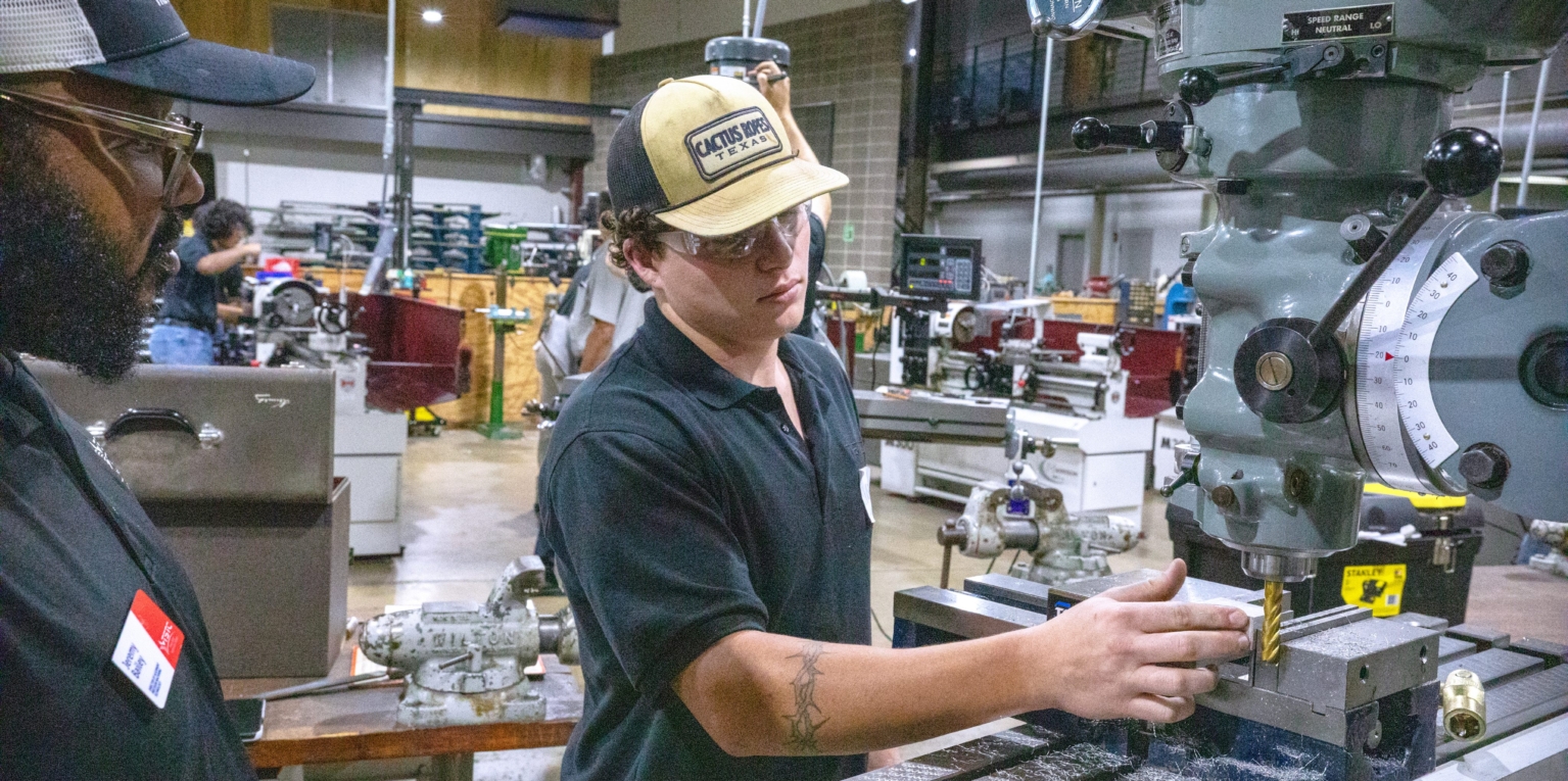 Photo caption: Texas State Technical College student Mason Clayton, of Graham, left, works during the Precision Machining program’s Machine Shop Mania competition Thursday, July 16, at the Waco campus. Looking on is Jeremy Bailey, TSTC’s director of alignment for the Precision Machining program. (Photo courtesy of TSTC.)