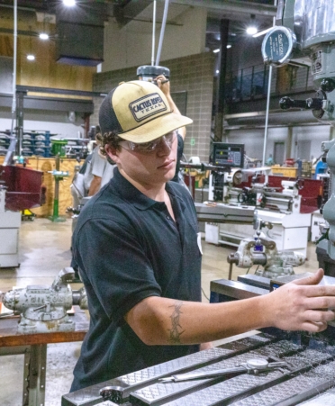 656A4282 copy (1) Photo caption: Texas State Technical College student Mason Clayton, of Graham, left, works during the Precision Machining program’s Machine Shop Mania competition Thursday, July 16, at the Waco campus. Looking on is Jeremy Bailey, TSTC’s director of alignment for the Precision Machining program. (Photo courtesy of TSTC.)