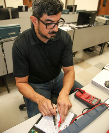 2R7A3696-2 Michael Plata, an Advanced Manufacturing student at Texas State Technical College’s Harlingen campus, measures voltage in a series circuit board during a lab session.